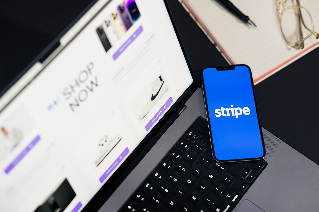 services-03 Mobile phone displaying Stripe app on a laptop with an eCommerce site open, symbolizing online shopping.